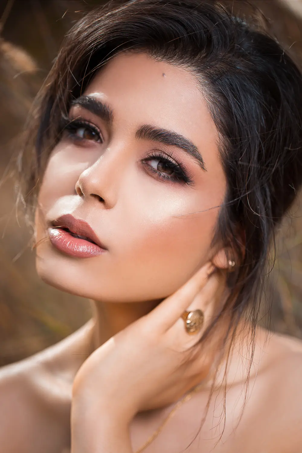 Mujer de piel trigueña, ojos miel posando en fondo oscuro con vestido negro un maquillaje social en manizales por daniela de maquela