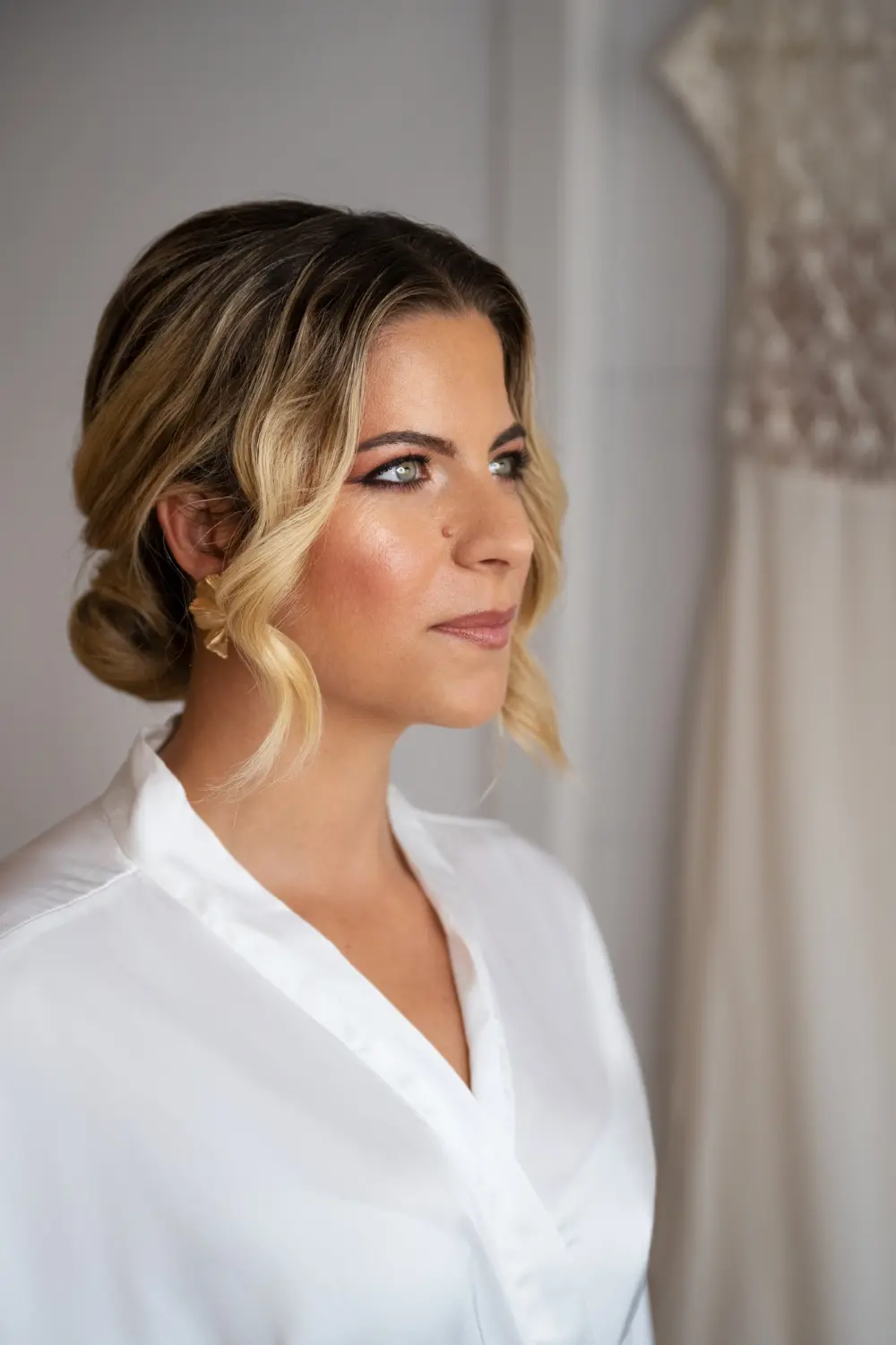Mujer de perfil en cuarto claro posando maquillaje y peinado antes de su boda
